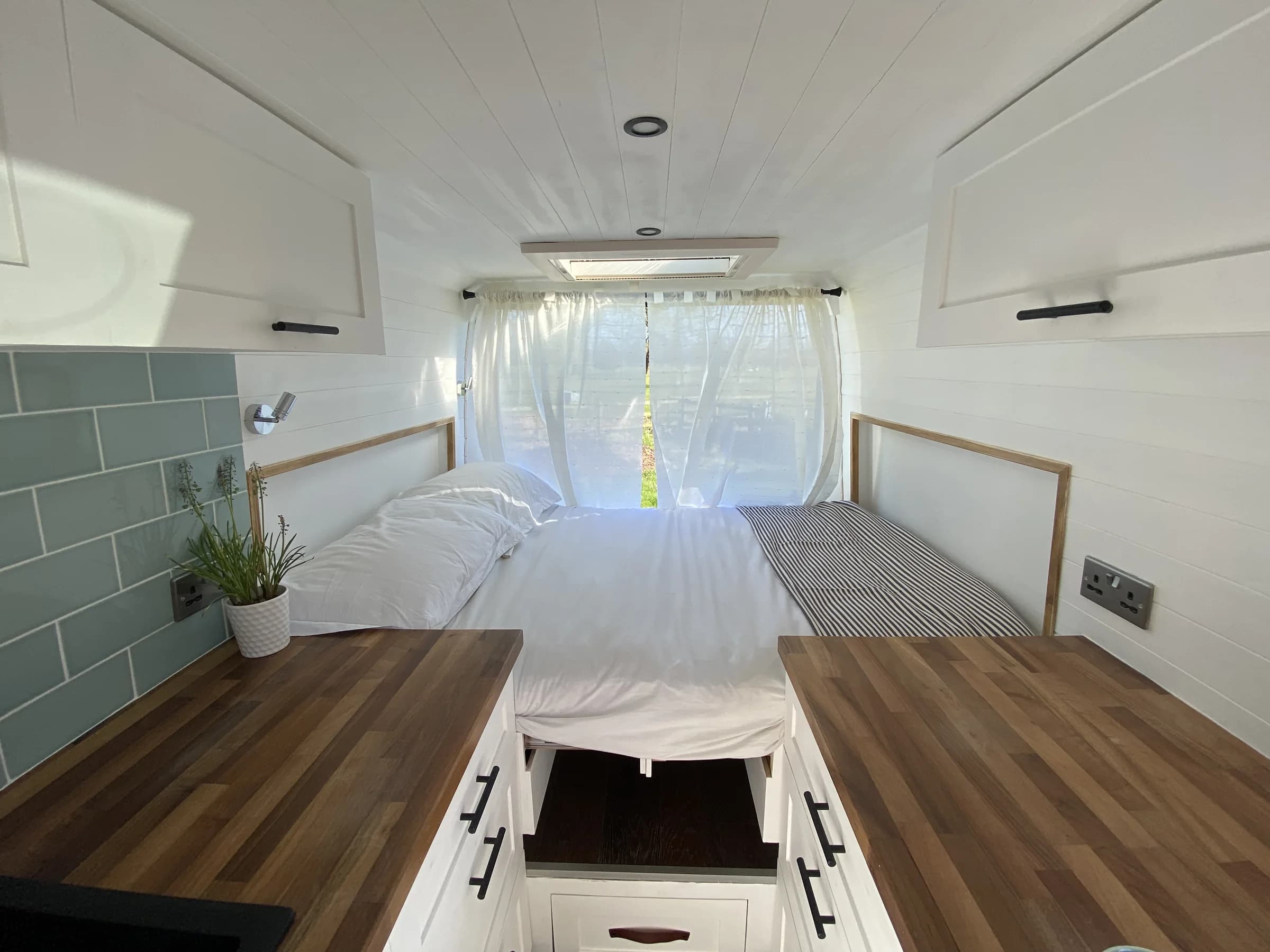 Convertible campervan bed made up between the galley units and side benches