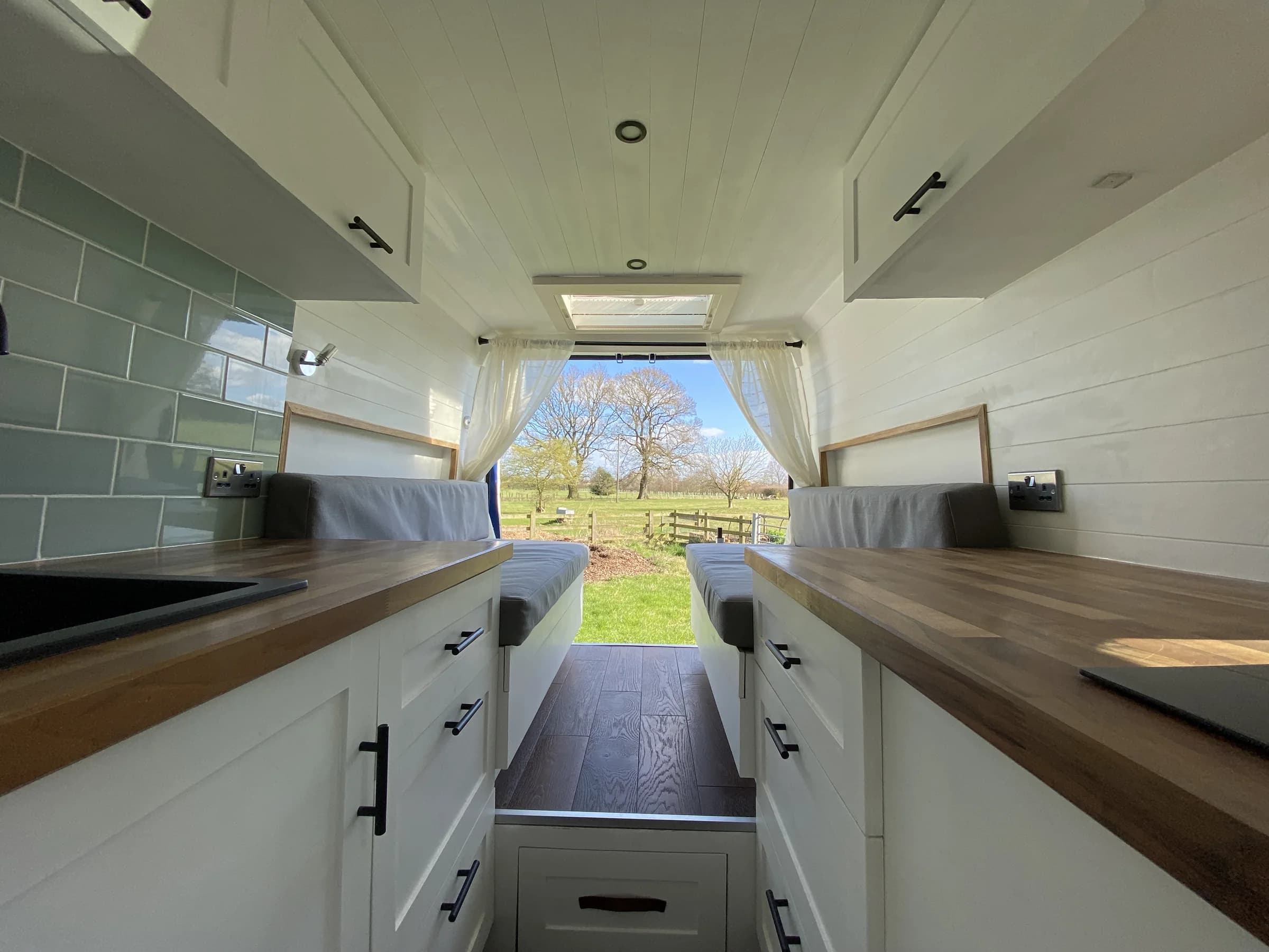 Finished campervan galley with timber worktops, sink, storage and induction hob
