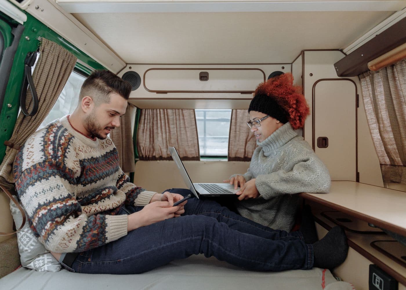 Two people using a laptop while planning from inside a campervan