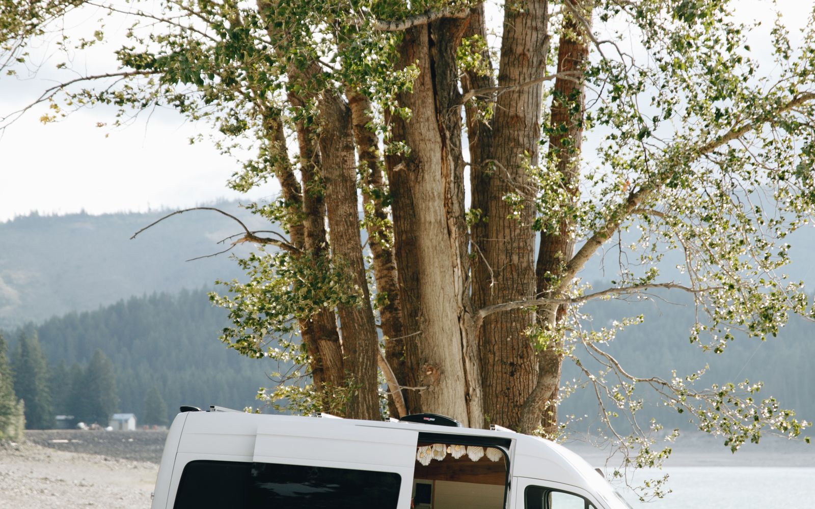 Camper van beside a lake in a forested clearing — Bend
