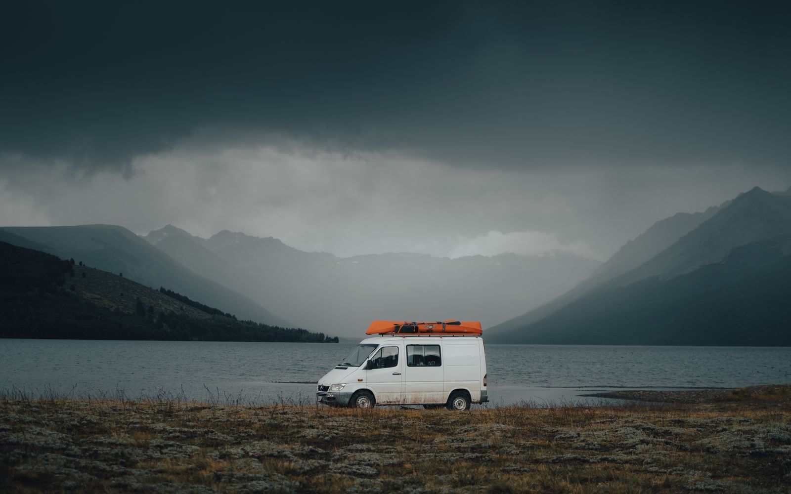 White campervan parked beside a misty mountain lake — Anglesey